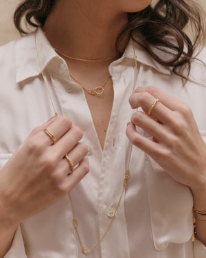 a woman wearing layered necklace including gold long dainty chain necklace 