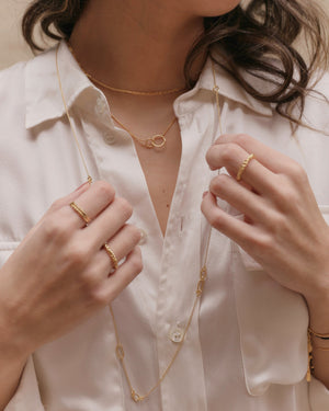  a woman wearing layered gold necklaces including interlocking_double_ring_necklace
