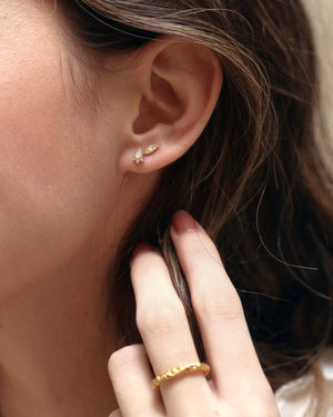 a close up of a woman wearing opal stud earrings with cubic zirconia